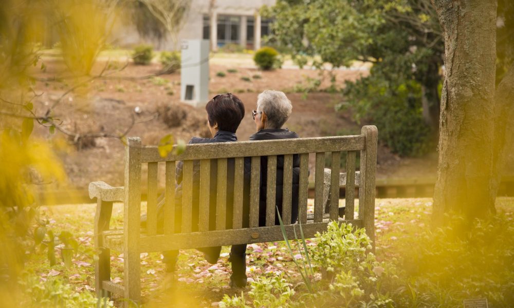 Woman sitting with an elderly woman on a bench outdoors
