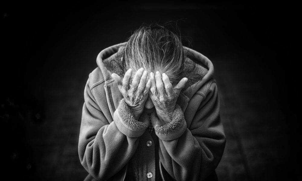 grayscale image of older woman with head in her hands