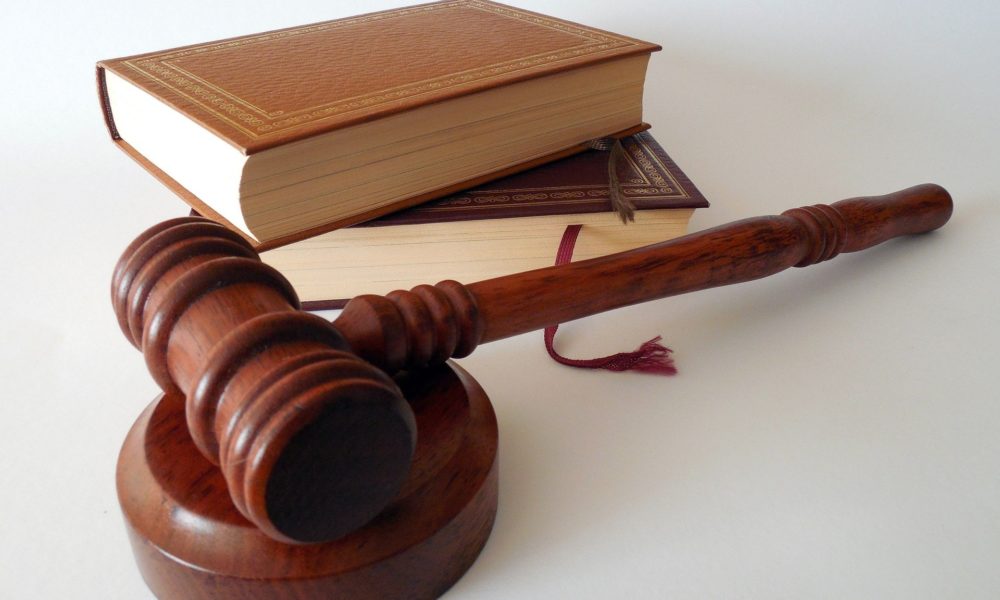 Photograph of a judge's gavel and sound block next two two books on top of each other