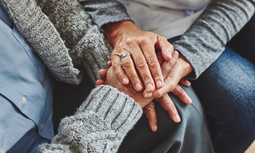 Photograph of a person holding another persons hand in their own hands