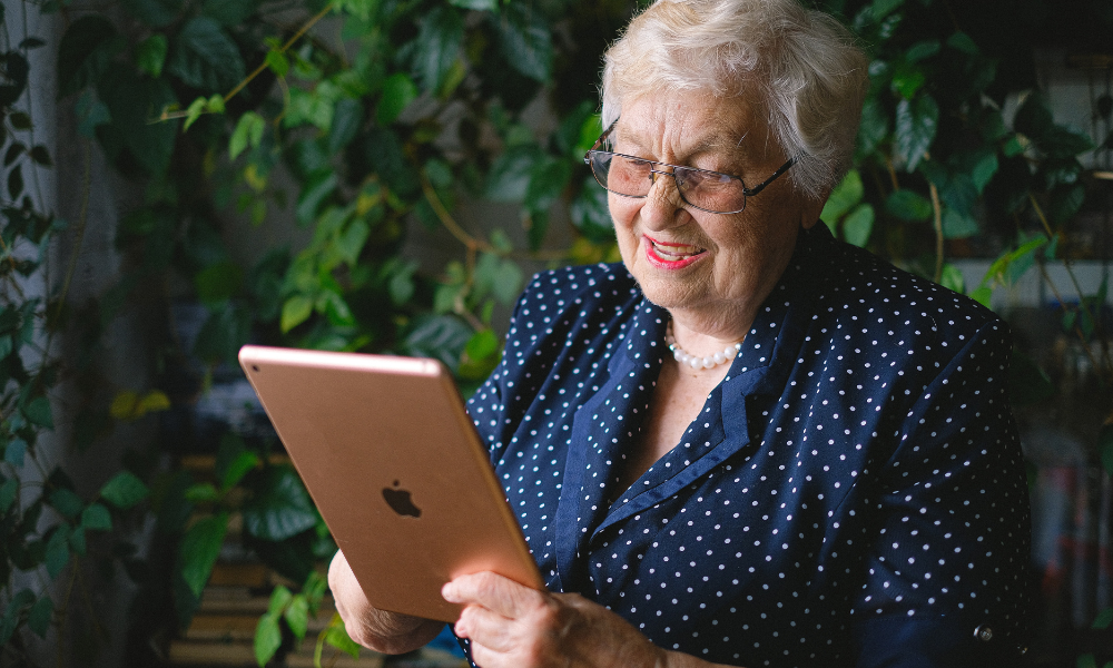 woman smiles while looking at the iPad in her hands. She asks, "How do I know if a website is trustworthy?"