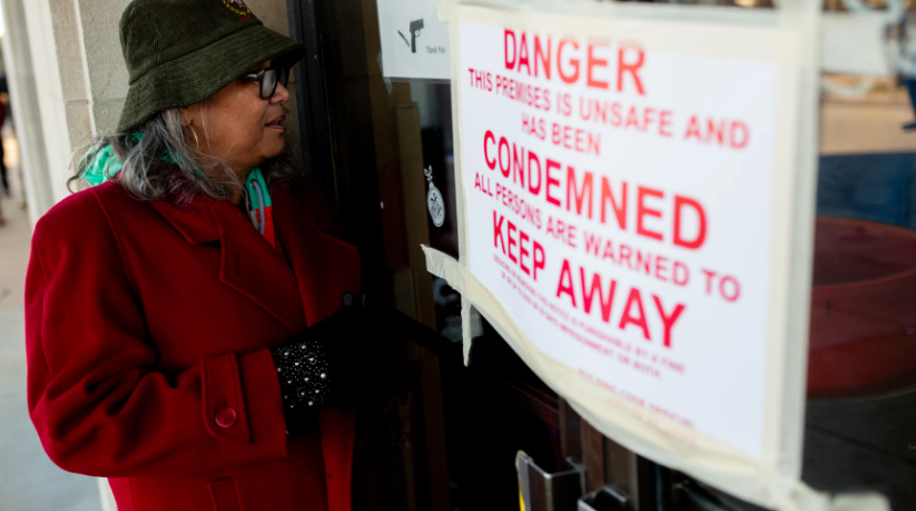 A woman looks into the closed Northview Village Nursing Home that has a Condemned sign on it.